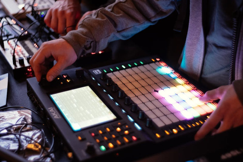 A DJ adjusts controls on a digital music mixer during a live performance indoors.